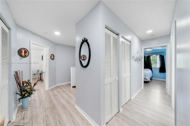 hall featuring light wood-style floors, recessed lighting, and baseboards
