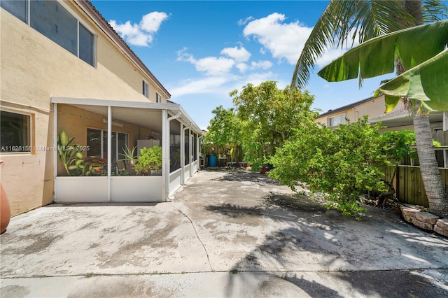 view of patio with a sunroom and fence