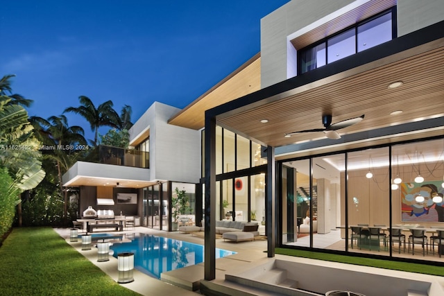 pool at night with an outdoor living space, ceiling fan, and a patio