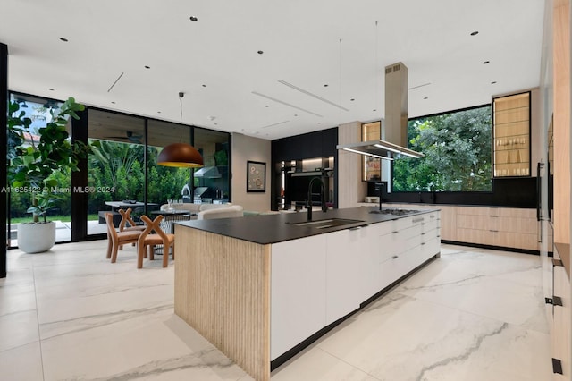 kitchen with pendant lighting, white cabinets, a center island with sink, sink, and island exhaust hood