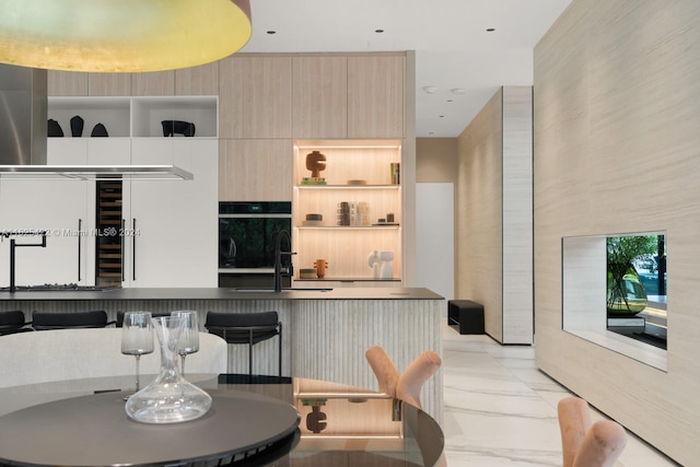 kitchen with light brown cabinets, double oven, and sink