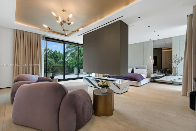 living room featuring an inviting chandelier, a wall of windows, and light hardwood / wood-style flooring