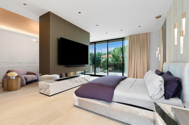 bedroom featuring access to exterior, light hardwood / wood-style floors, and a wall of windows