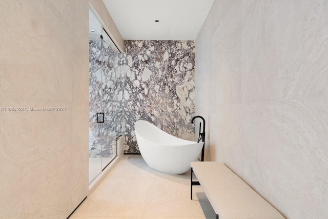 bathroom featuring tile patterned flooring, a bath, and tile walls