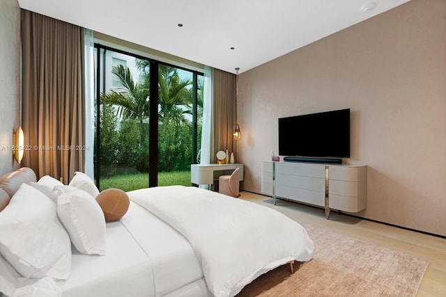 bedroom with floor to ceiling windows, access to exterior, and light wood-type flooring