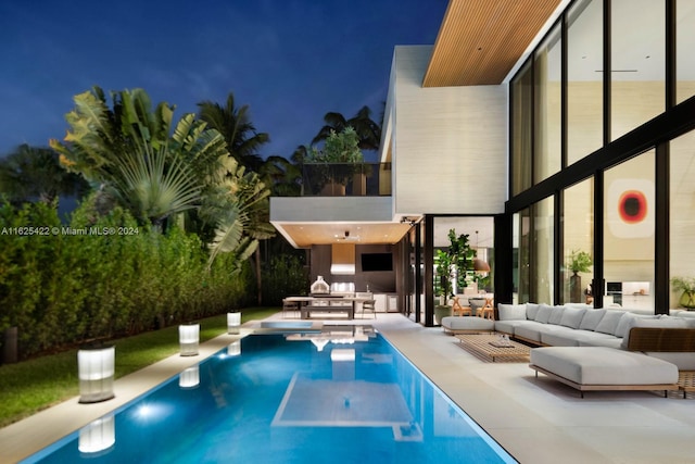 pool at night with an outdoor hangout area and a patio