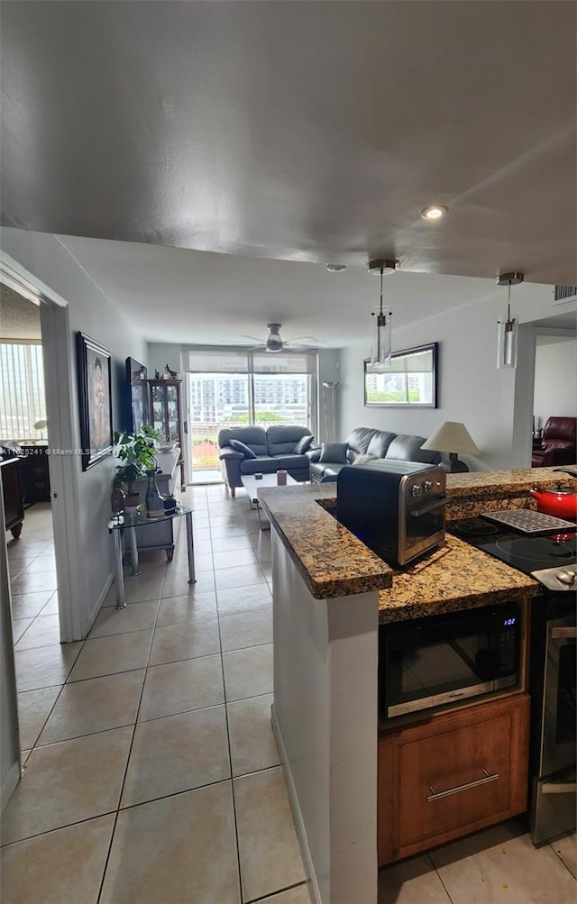 kitchen with built in microwave, electric stove, light tile patterned floors, dark stone counters, and open floor plan