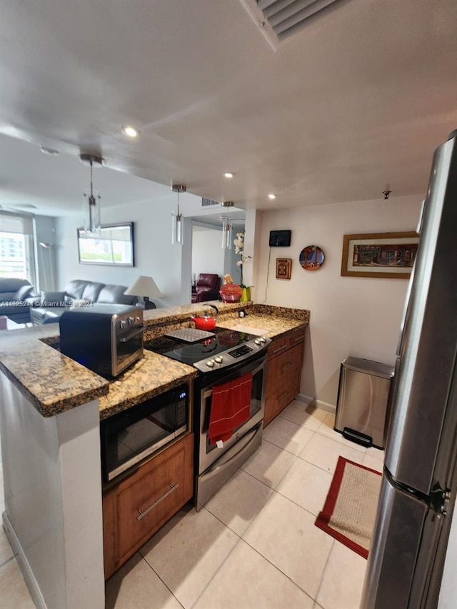 kitchen featuring a peninsula, appliances with stainless steel finishes, open floor plan, and light stone counters