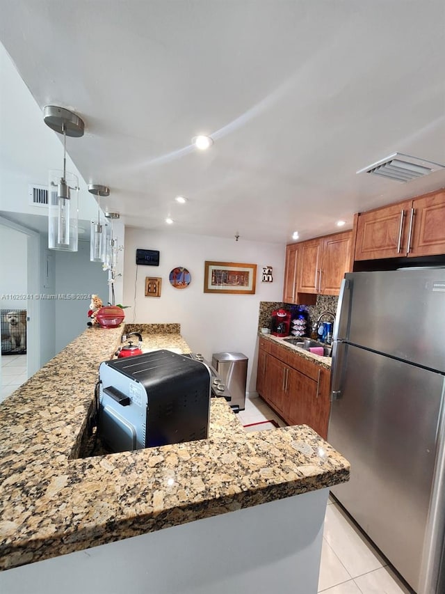 kitchen with brown cabinets, light tile patterned flooring, and freestanding refrigerator