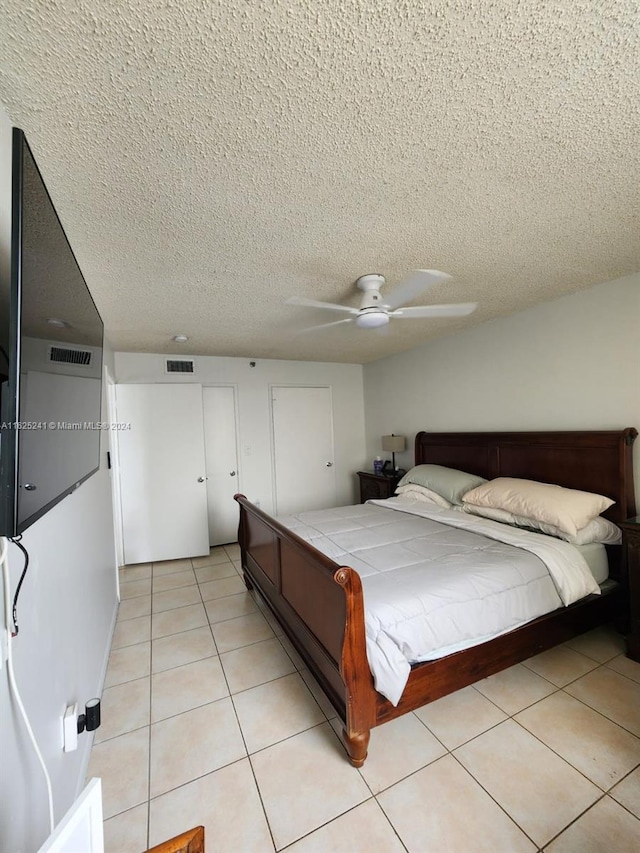bedroom featuring a textured ceiling, visible vents, a ceiling fan, and light tile patterned floors