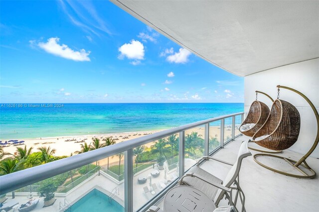 balcony featuring a water view and a beach view