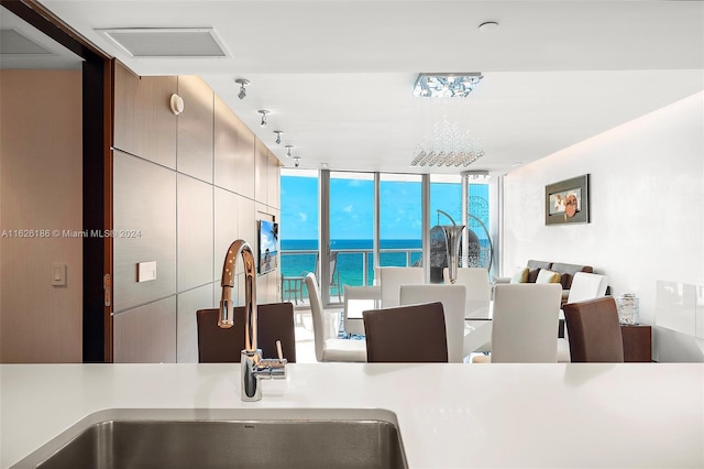 kitchen with sink, track lighting, floor to ceiling windows, and a water view