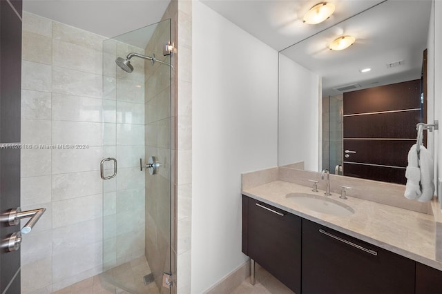 bathroom featuring a shower with door and vanity