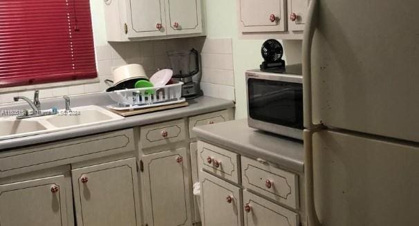 kitchen with sink, appliances with stainless steel finishes, white cabinets, and backsplash