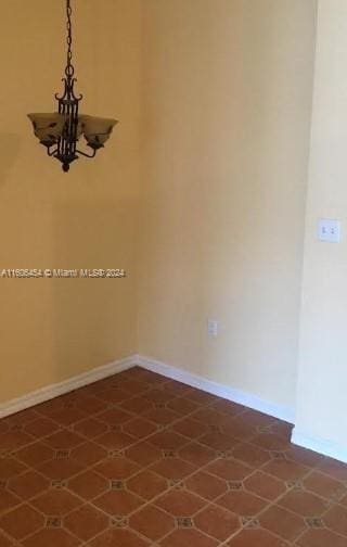 spare room with an inviting chandelier and tile patterned flooring