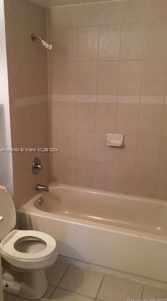 bathroom featuring toilet, tile patterned floors, and tiled shower / bath