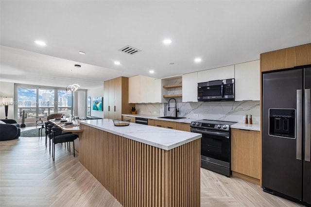 kitchen featuring light parquet floors, decorative light fixtures, black appliances, a kitchen island, and backsplash