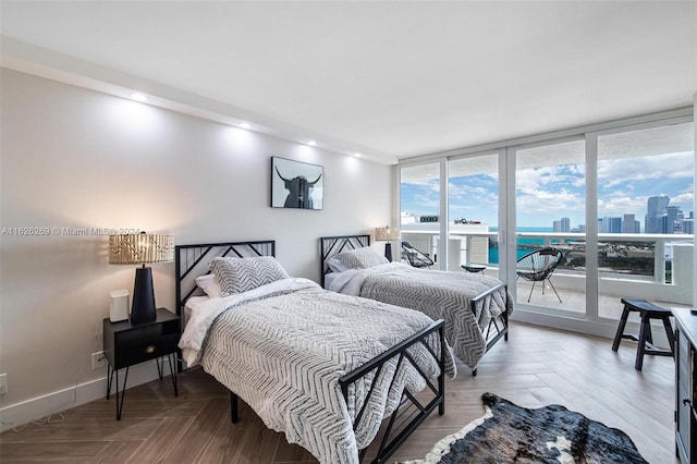 bedroom with parquet floors, expansive windows, multiple windows, and access to outside