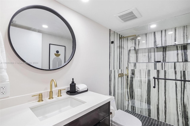 bathroom with vanity, a tile shower, and toilet