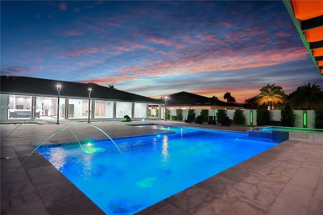 pool at dusk featuring a patio and pool water feature