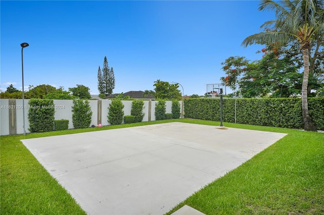 view of sport court with a lawn