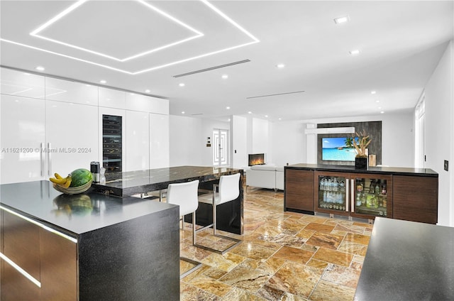 kitchen with white cabinets, a kitchen island, and wine cooler