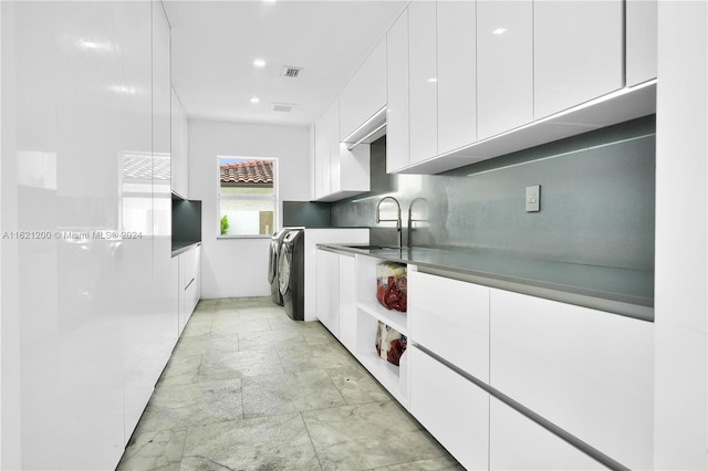 kitchen featuring washer / dryer, white cabinetry, and sink