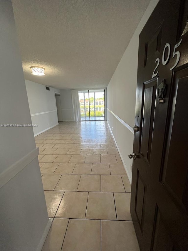 corridor featuring a textured ceiling and light tile patterned floors