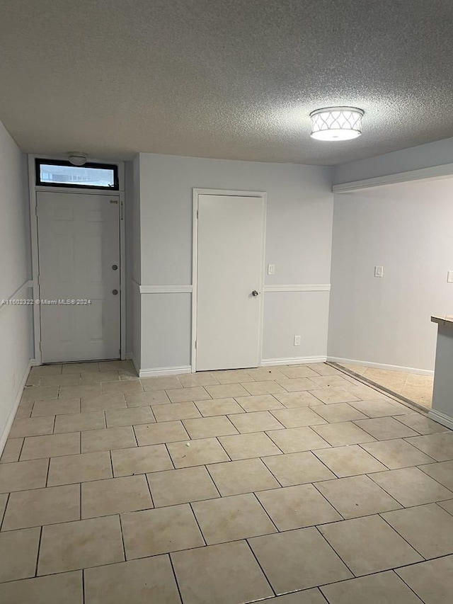 tiled empty room featuring a textured ceiling