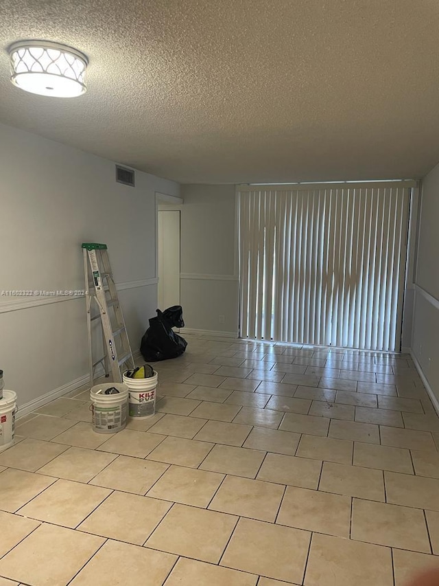 tiled empty room featuring a textured ceiling