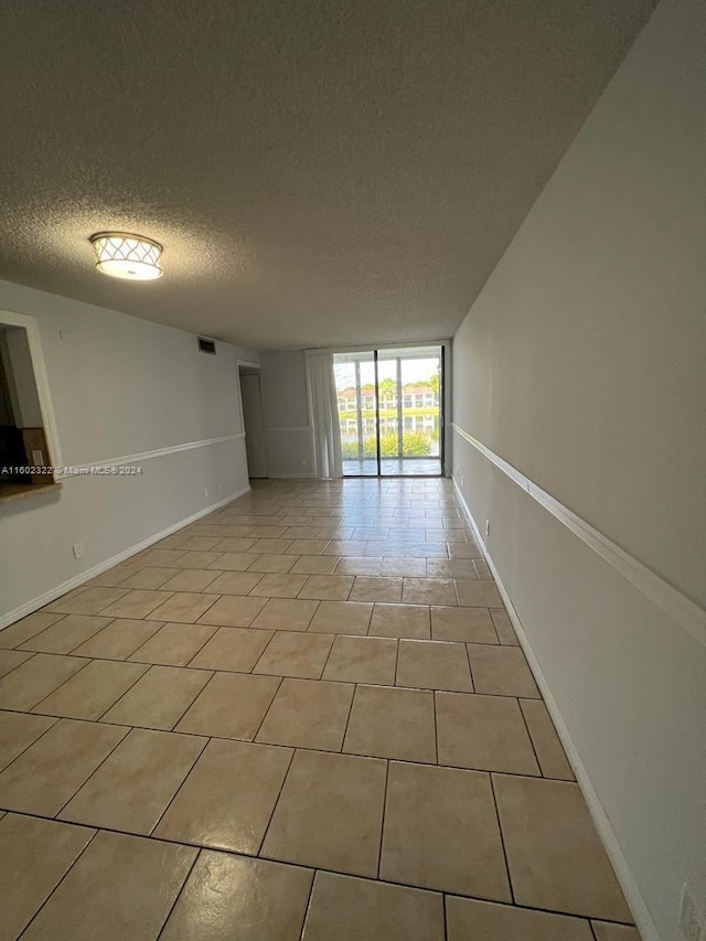 empty room with light tile patterned flooring and a textured ceiling