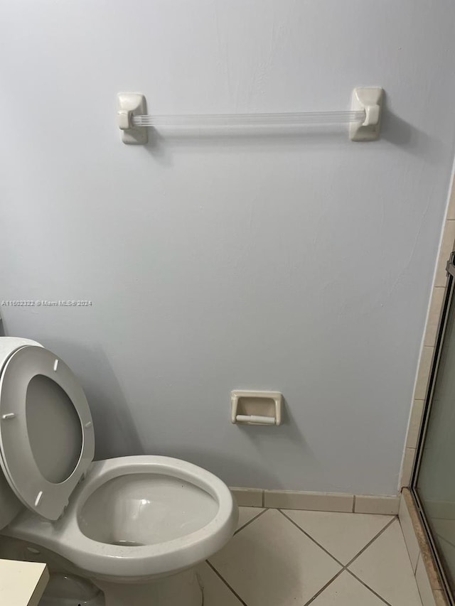 bathroom with a shower with shower door, tile patterned floors, and toilet