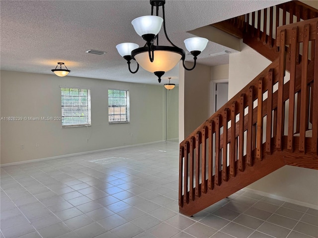 staircase with a textured ceiling, tile patterned flooring, visible vents, and baseboards