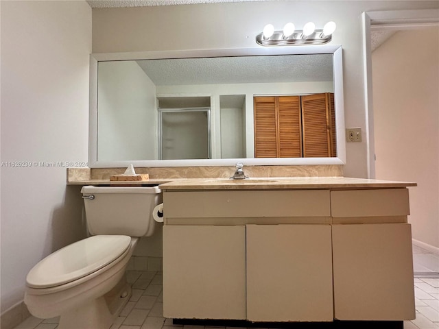 bathroom with toilet, a shower stall, a textured ceiling, and vanity