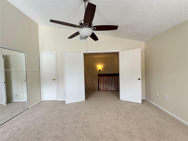 unfurnished bedroom with carpet, visible vents, vaulted ceiling, and a textured ceiling