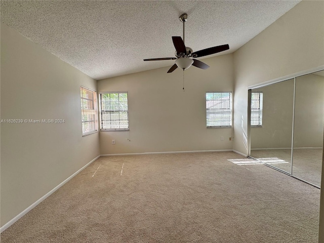 unfurnished bedroom featuring multiple windows, vaulted ceiling, and light colored carpet