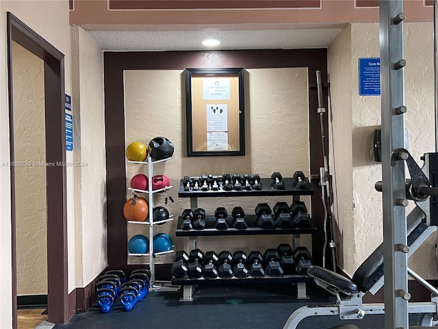 exercise room featuring a textured ceiling and a textured wall