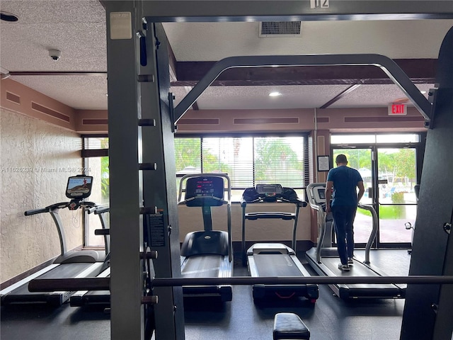 exercise room with a textured ceiling, a textured wall, and visible vents