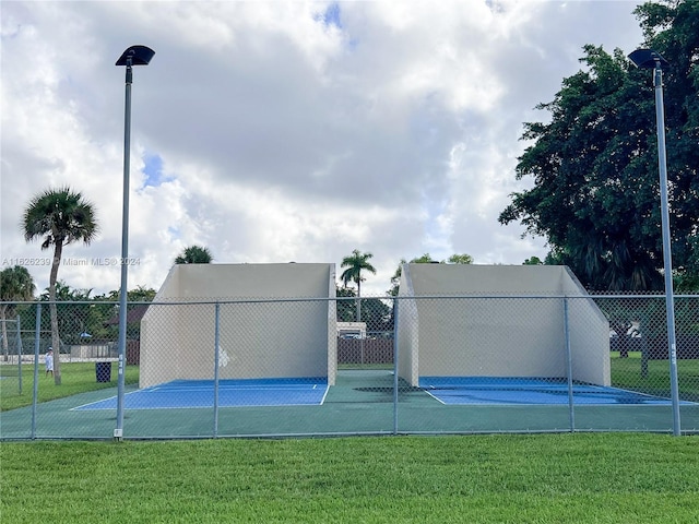 view of sport court with a yard and fence