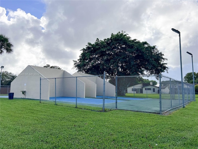 view of sport court with a yard and fence