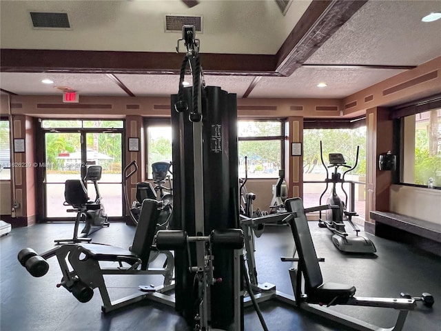 workout area with baseboards, visible vents, and a textured ceiling