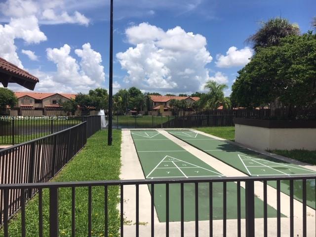 view of home's community with shuffleboard, a yard, and fence