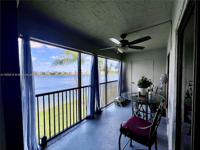 sunroom featuring a water view and ceiling fan