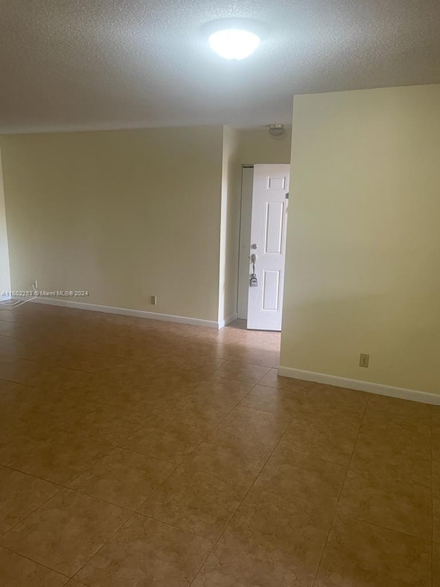 tiled spare room with a textured ceiling