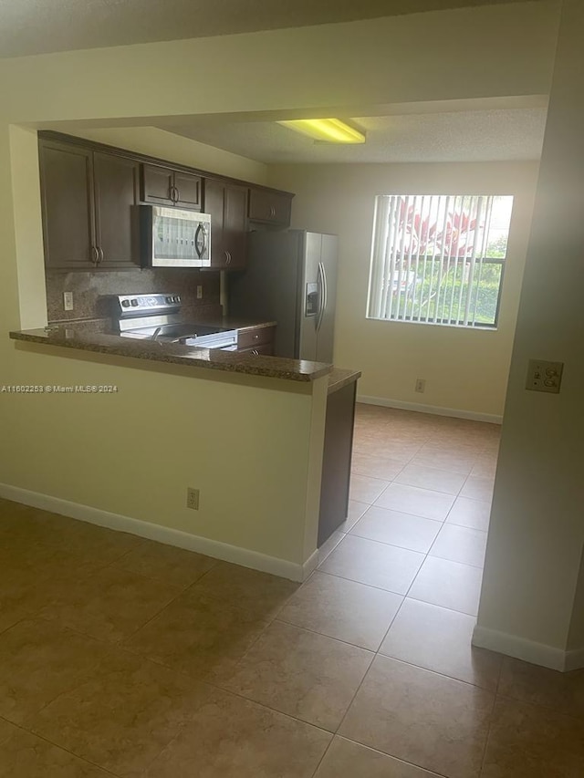 kitchen featuring fridge with ice dispenser, kitchen peninsula, backsplash, white range with electric stovetop, and dark brown cabinetry