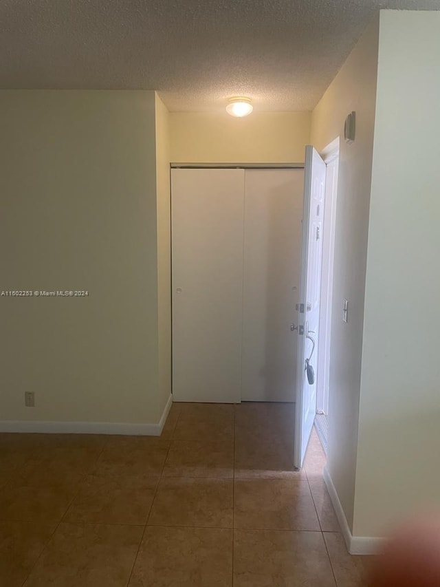 corridor with tile patterned floors and a textured ceiling