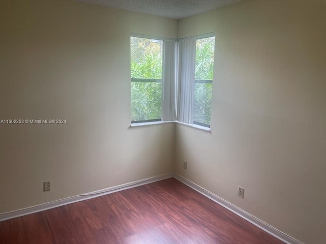 unfurnished room featuring a textured ceiling, wood-type flooring, and plenty of natural light