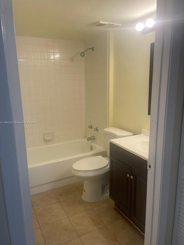 full bathroom with tiled shower / bath combo, vanity, tile patterned floors, and toilet