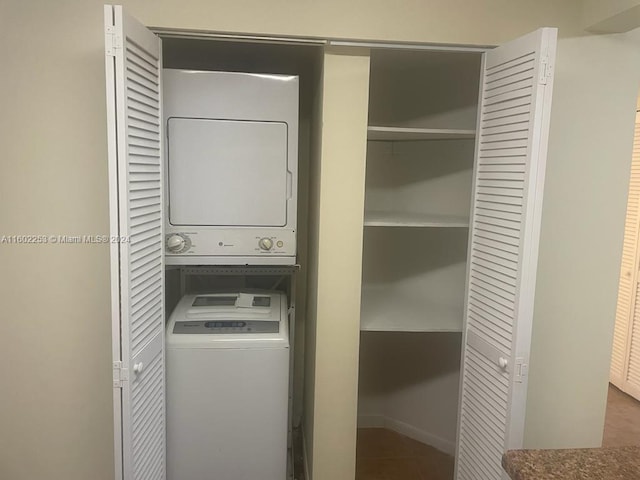 laundry area with stacked washer / dryer and tile patterned flooring