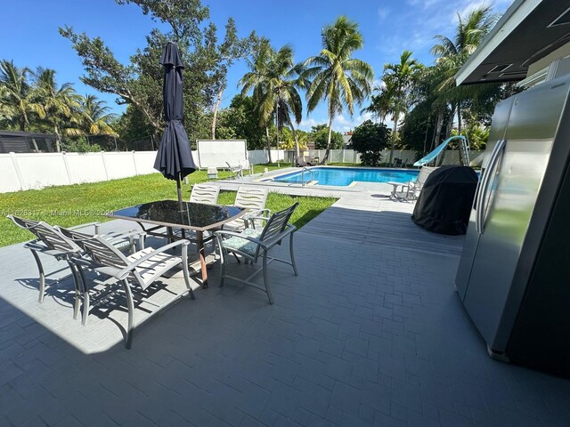 view of swimming pool featuring a water slide, a lawn, and a patio area